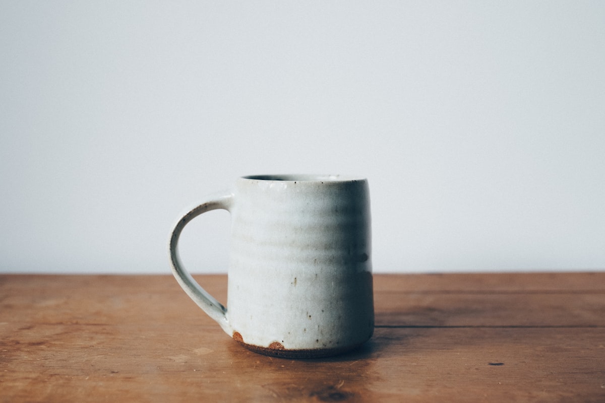 Handmade speckled stoneware mug on a wooden table
